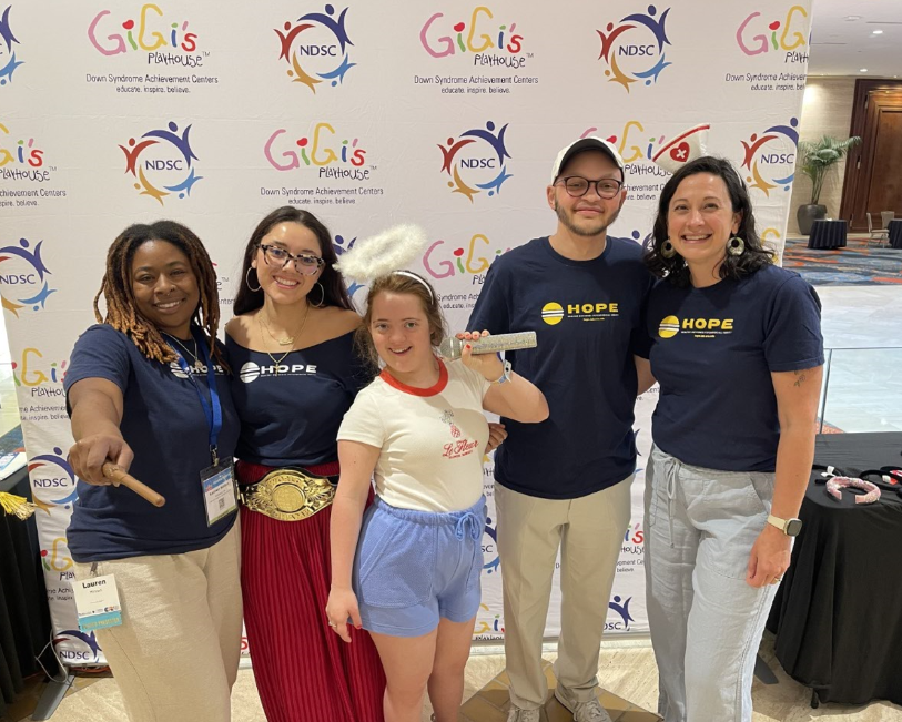 Group of smiling people wearing funny props in front of a backdrop printed with NDSC and Gigi's logos