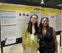 Two students standing by a research poster
