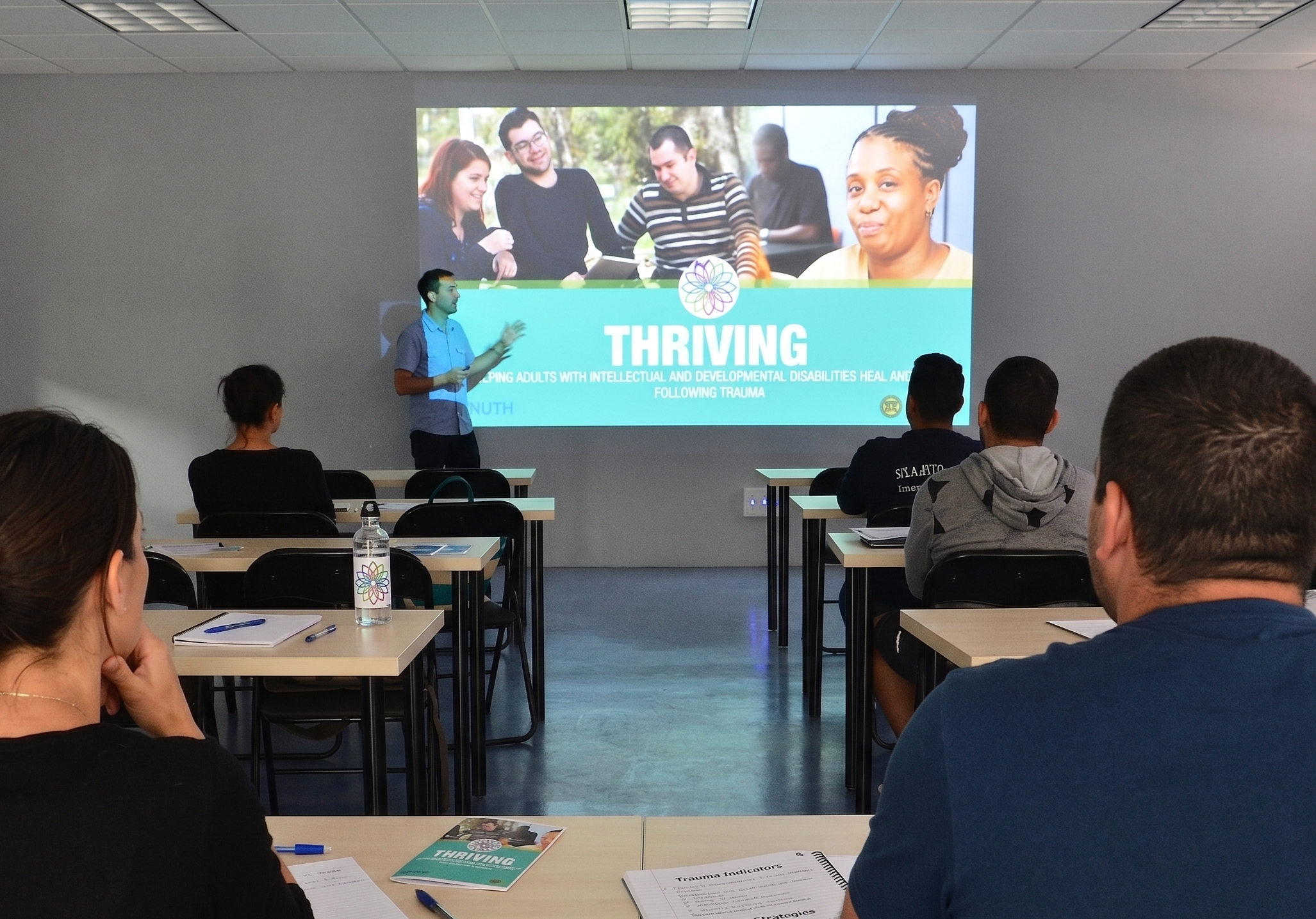 Picture of a classroom with a person presenting the Thriving Course